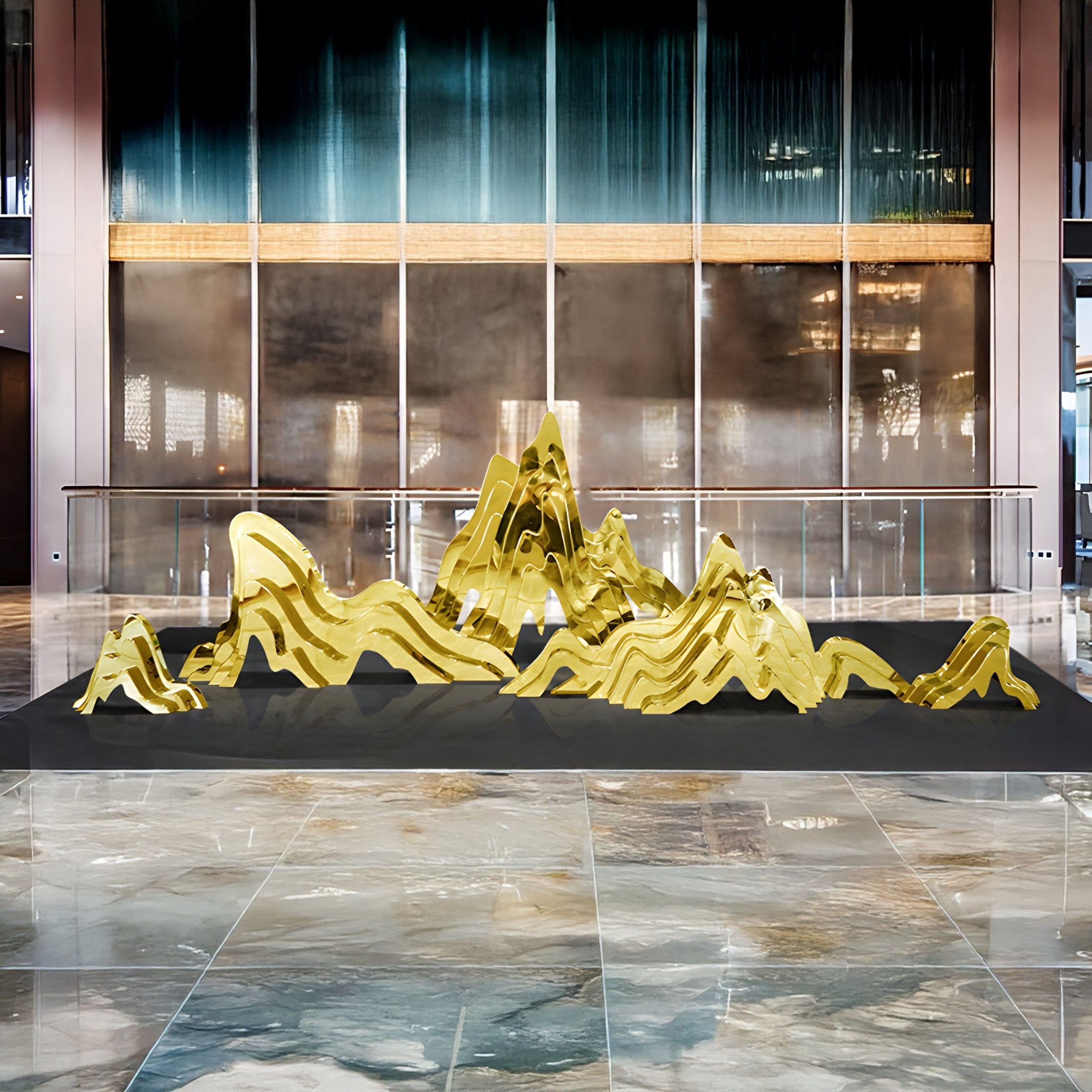 The Mountain Range Gold Abstract Steel Sculpture by Giant Sculptures stands on a black platform in a spacious lobby with reflective floors, tall glass windows, and pillars, creating a sleek contemporary ambiance that highlights this stunning piece of modern art.