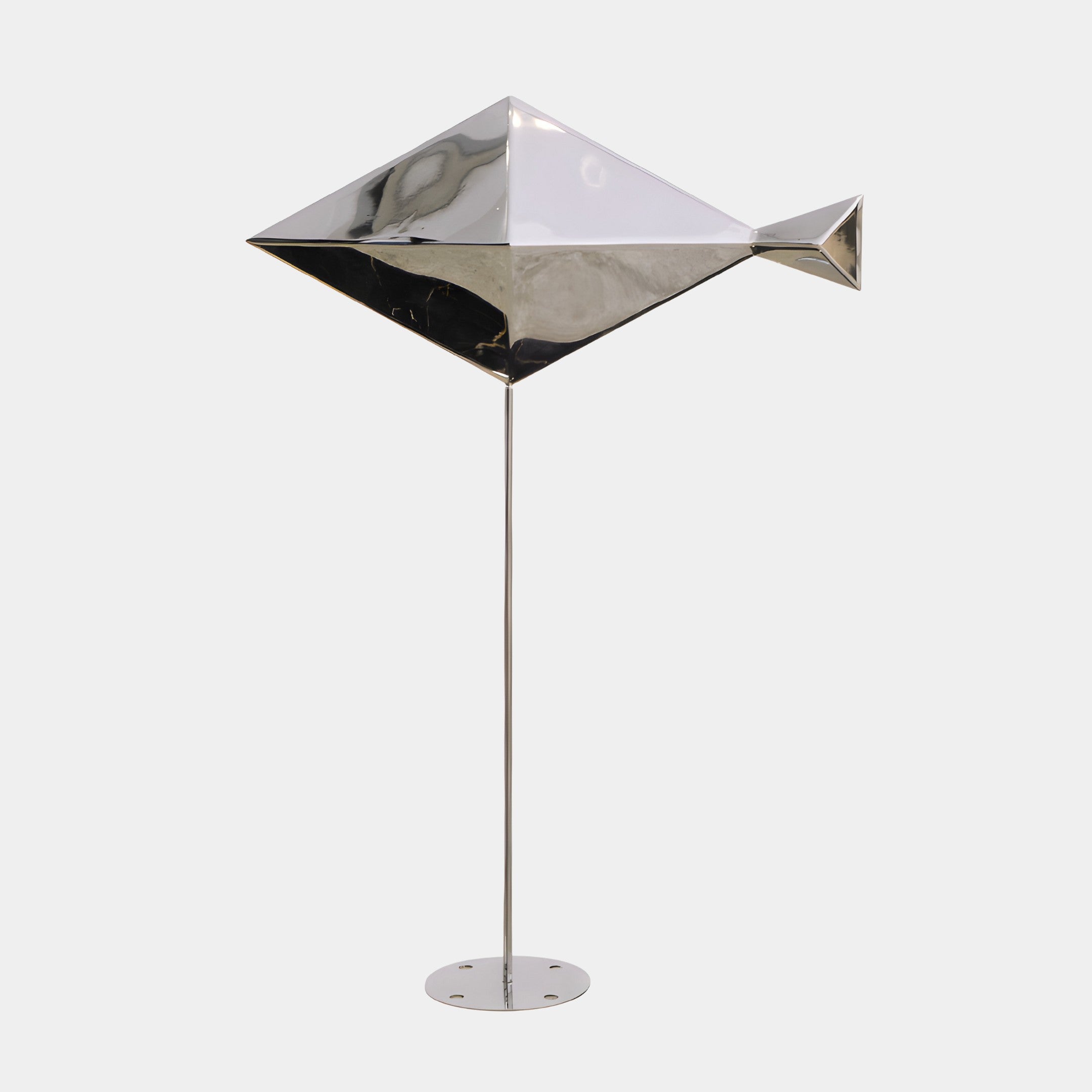 A geometric fish sculpture in silver, mounted on a tall metal stand.