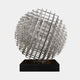 The Mesh Silver Geometric Steel Sculpture - 135/200cm by Giant Sculptures features an intricate design of interlocking rectangular steel rods that form a spherical shape. It is mounted on a black square base, showcasing a detailed pattern of lines and angles. The plain white background accentuates the modern artistry's elaborate details.