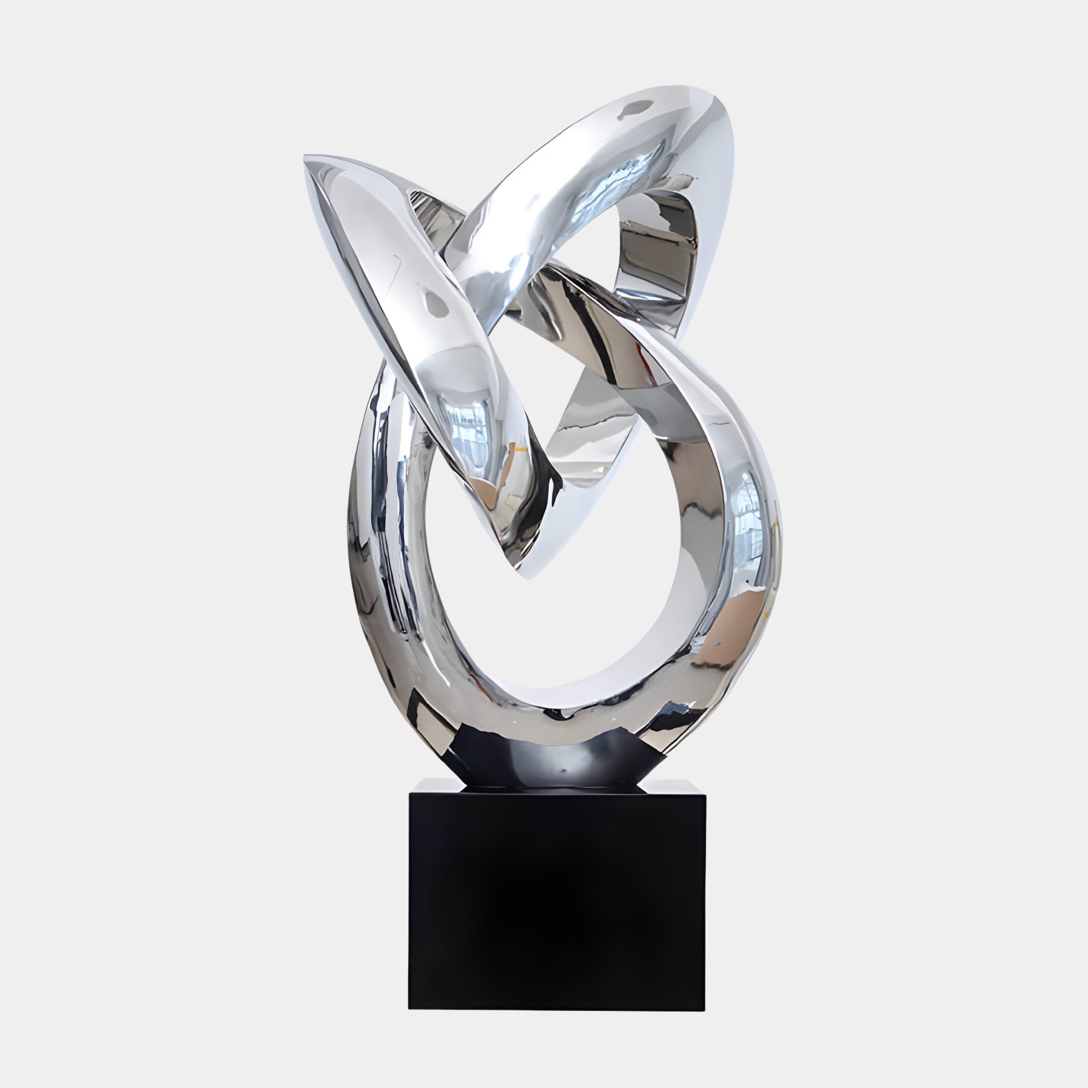 A large, modern silver sculpture with interlocking circular and angular forms, placed on a black base.