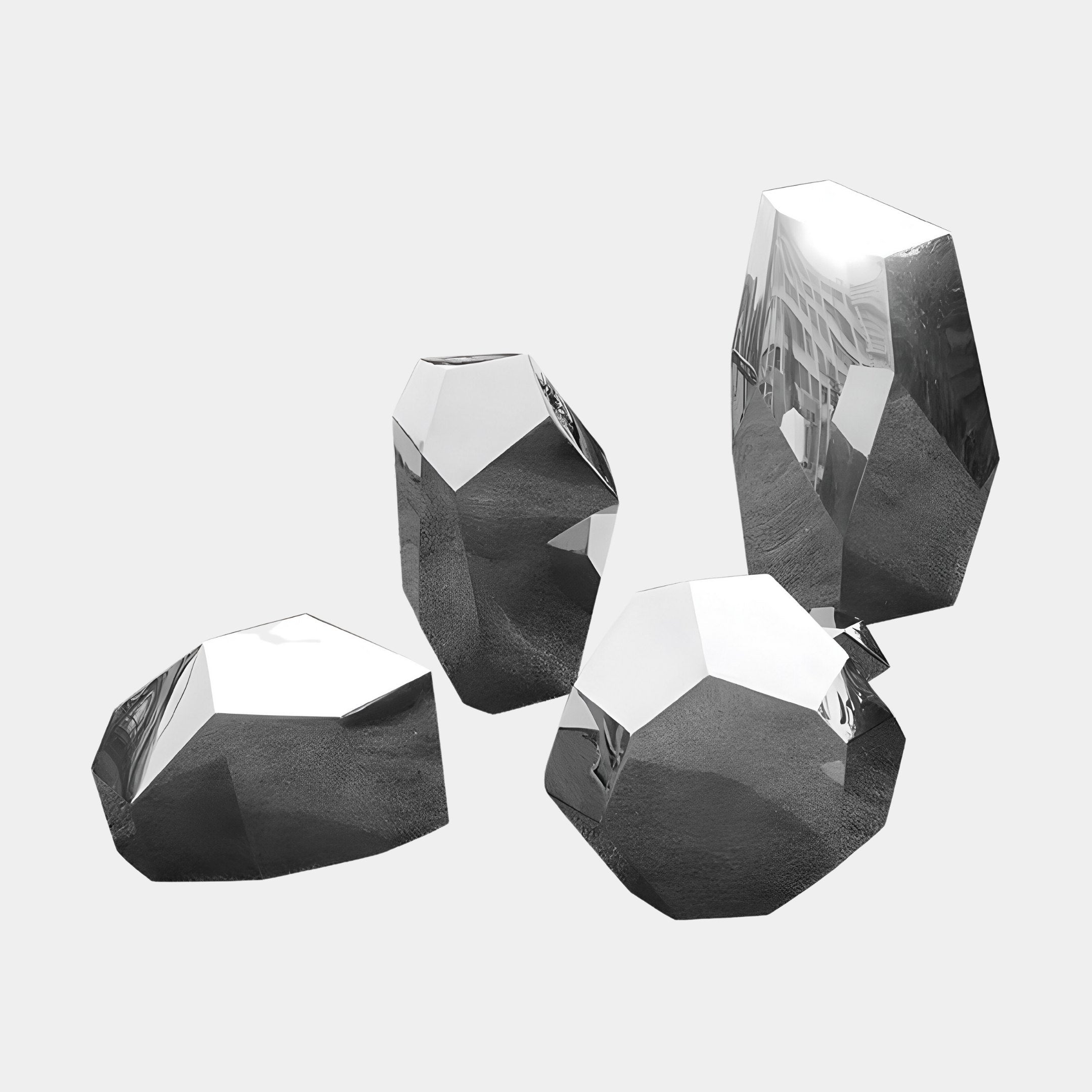 A collection of four Tetra Geometric Steel Rock Sculptures from Giant Sculptures is arranged on a simple, light background. These reflective metallic pieces, each varying in height and shape, exhibit a dazzling mirror-like finish that captures and artfully distorts nearby reflections in an enchanting display.