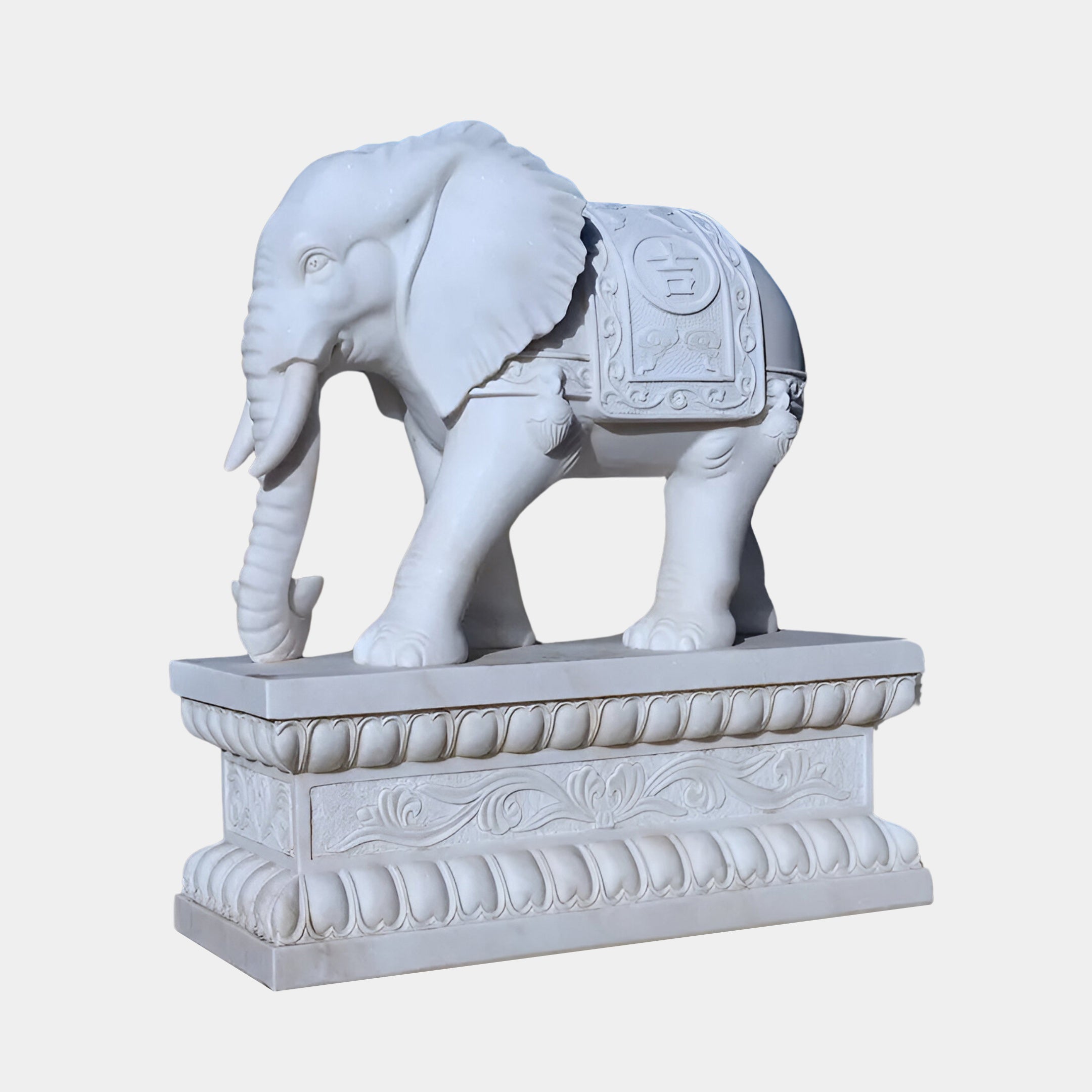 The Lucky Chinese Elephant Marble Outdoor Sculpture by Giant Sculptures stands 180cm tall and features a white elephant with ornate carvings, including a decorative cloth with a circular emblem on an intricate floral pedestal that reflects the elegance of Chinese heritage.