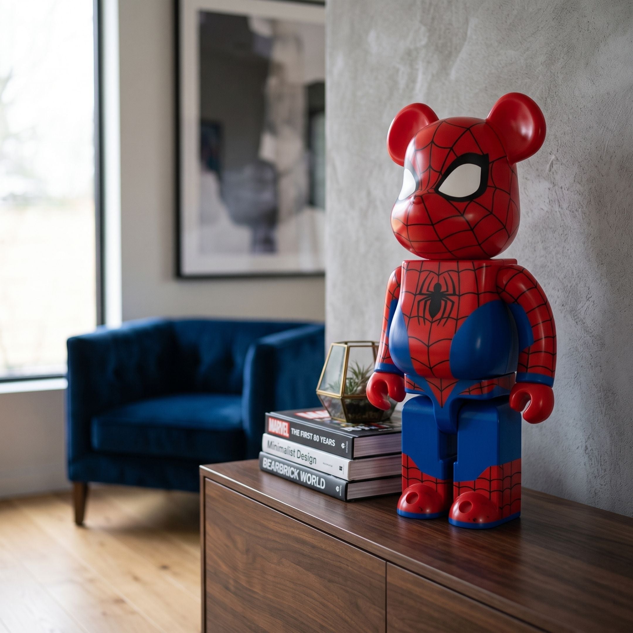 Glossy Spidey Web Bear Sculpture (70cm) in red and blue high-gloss resin with black web detailing, displayed on a wood console beside stacked books in a living room.