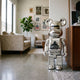 Gorilla Crest Chrome Bear Sculpture, 70cm, mirror-chrome silver finish with XLARGE crest, standing in a living room beside a wooden cabinet and sofas.