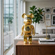 Gorilla Crest Gold Bear Sculpture (70cm) in gold electroplate finish on a wooden sideboard in a living room with grey sofas and framed wall art.