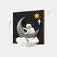 Giant Sculptures 3D MoonSail Astronaut Starry Wall Art features an astronaut fishing for dreams on a crescent moon amidst clouds. Set on a black square, it includes stars and a ringed planet with three white star shapes, capturing playful space exploration.