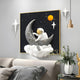 The 3D MoonSail Astronaut Starry Wall Art by Giant Sculptures shows an astronaut on a crescent moon holding a flag against a cosmic background. Below, decor and a vase with greenery rest on the shelf, lit by an overhead pendant light.