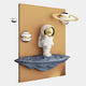The Giant Sculptures White 3D Stardust Astronaut Wall Art features a resin astronaut holding a star on a rocky base, with two gold-ringed planets and a brown rectangular backdrop for a cosmic décor touch.