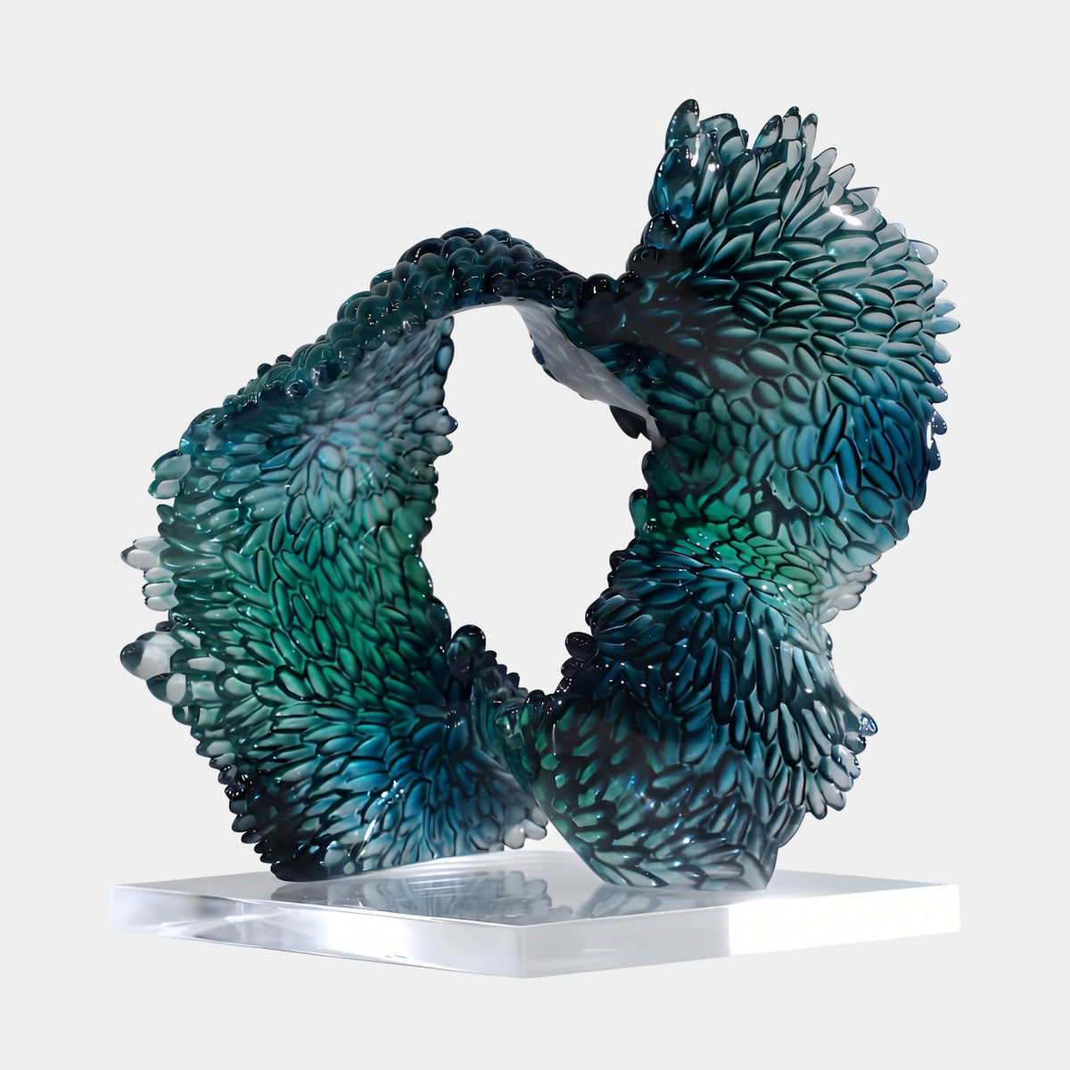 Teal Overlapping Scale Loop Resin Sculpture (35cm) by Giant Sculptures, a looped form of overlapping teardrop scales in petrol teal to green, on a clear acrylic base against a plain white background.