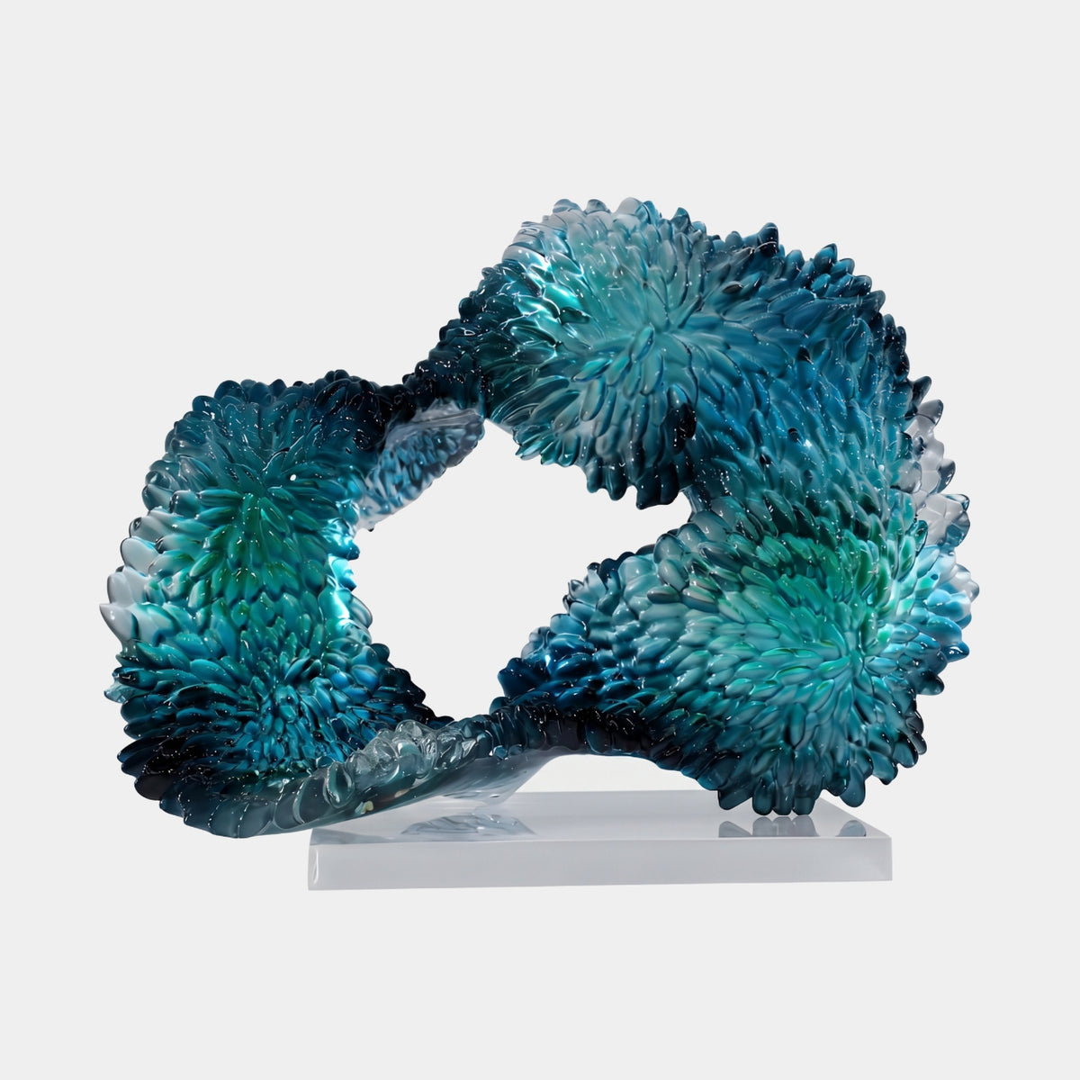 Teal Rosette-Scaled Closed Loop Resin Sculpture (44cm) by Giant Sculptures, a closed loop covered in pointed teal rosette scales fading to clear, mounted on a clear block against a light grey background.
