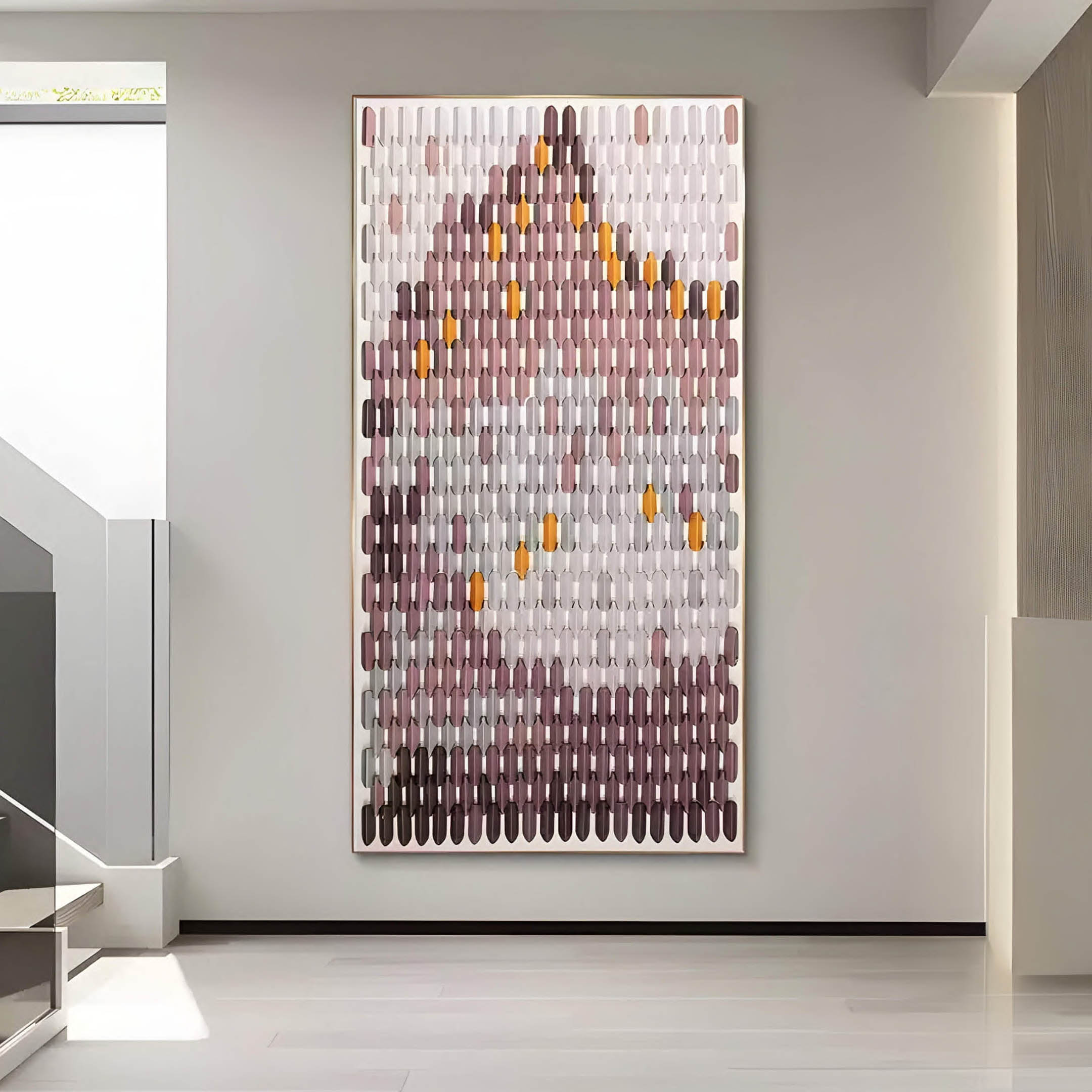 The Artevo 3D Ceramic Wall Art by Giant Sculptures adorns a gallery wall with its sculptural vertical pattern of elongated shapes in plum, amber, and gray, forming a mountain-like silhouette. The minimalist setting with neutral walls and flooring exudes contemporary flair.