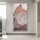 The Artevo 3D Ceramic Wall Art by Giant Sculptures adorns a gallery wall with its sculptural vertical pattern of elongated shapes in plum, amber, and gray, forming a mountain-like silhouette. The minimalist setting with neutral walls and flooring exudes contemporary flair.