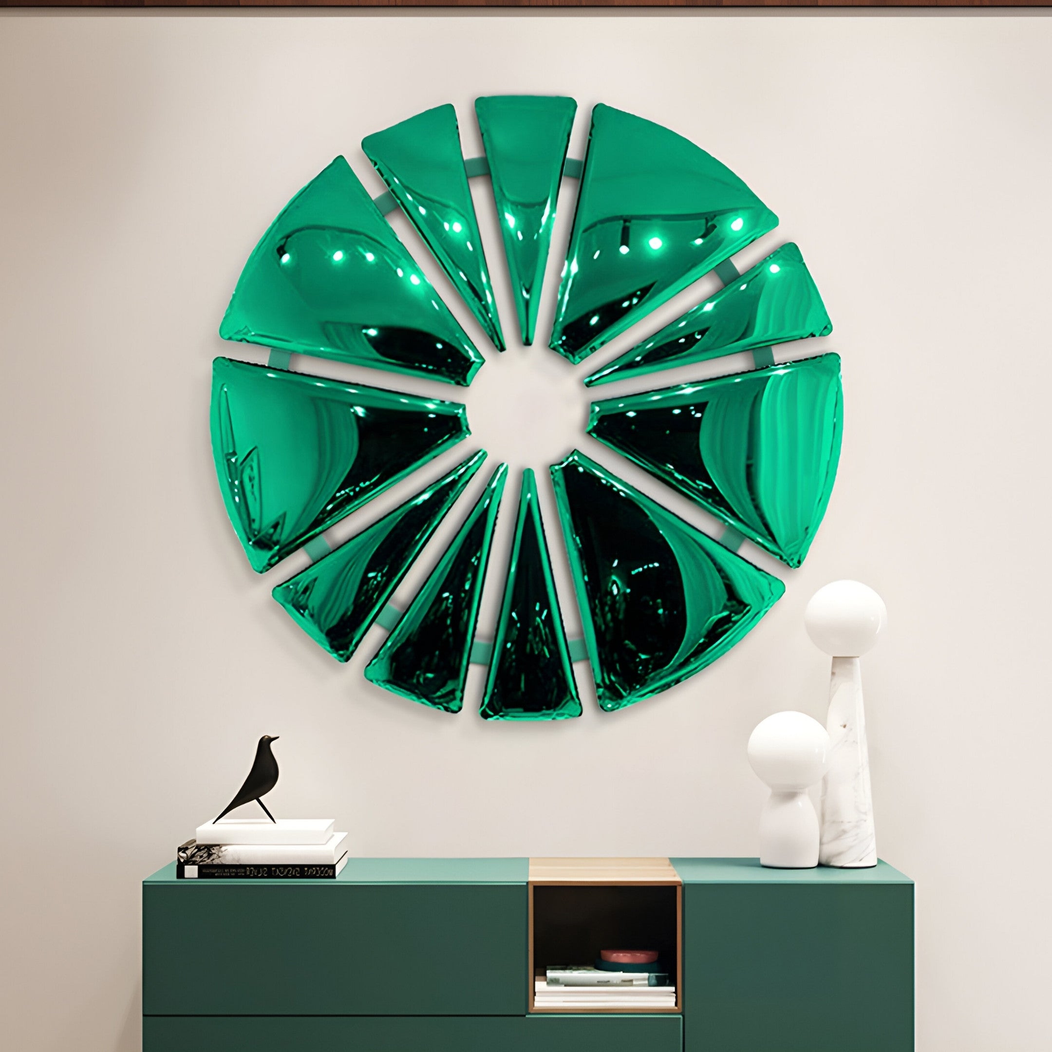 The Halo Emerald Segment Circle 3D Metal Wall Art by Giant Sculptures decoratively adorns a light wall above a modern teal cabinet, which displays a black bird figurine, stacked books, and two white spherical lamps.