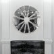 The Halo Chrome Segment Circle 3D Metal Wall Art by Giant Sculptures, with its reflective chrome design, forms a stunning sunburst pattern on the wall. Below it, a marble-topped console table featuring dark textures adds a sophisticated touch to the modern decor.