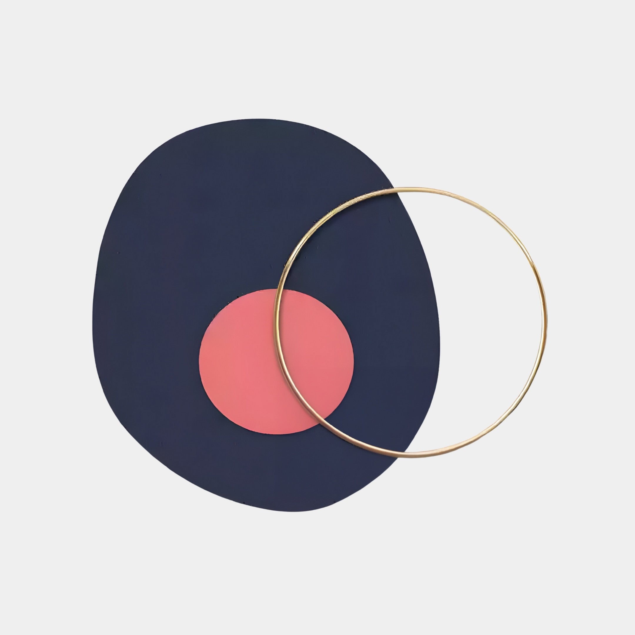 The Solaro Bold Navy & Coral Round Mural Wall Art by Giant Sculptures is a Nordic-inspired piece featuring a navy blue oval with a pink circle inside, overlapped by a thin gold ring on a white background.