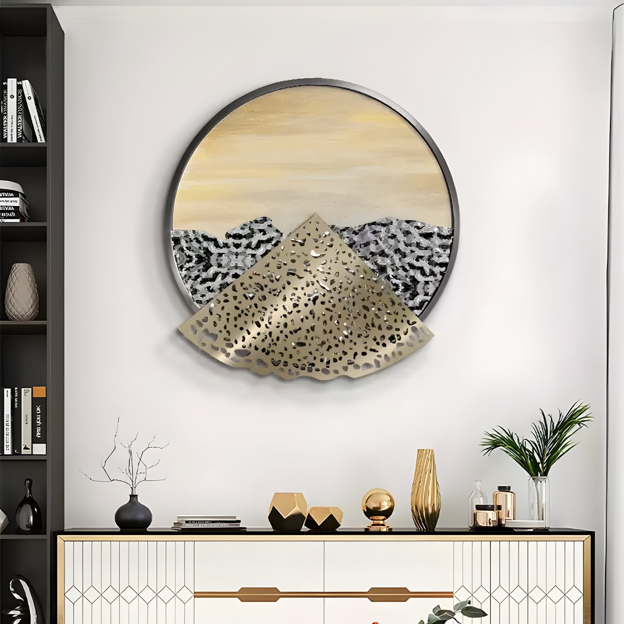 A modern living room showcases the Aurelio Bottom Metallic Layered Textured Round Wall Art by Giant Sculptures. A sleek console table below displays geometric decor, a vase with branches, and a small potted plant. Flanked by bookshelves, the scene radiates modern elegance.