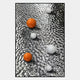 Two orange and four white spheres rest on a rippled, reflective metallic surface in this striking Luminosa Orange & White Orb Textured Metal Wall Art by Giant Sculptures, perfect for contemporary interiors and those seeking abstract decor.