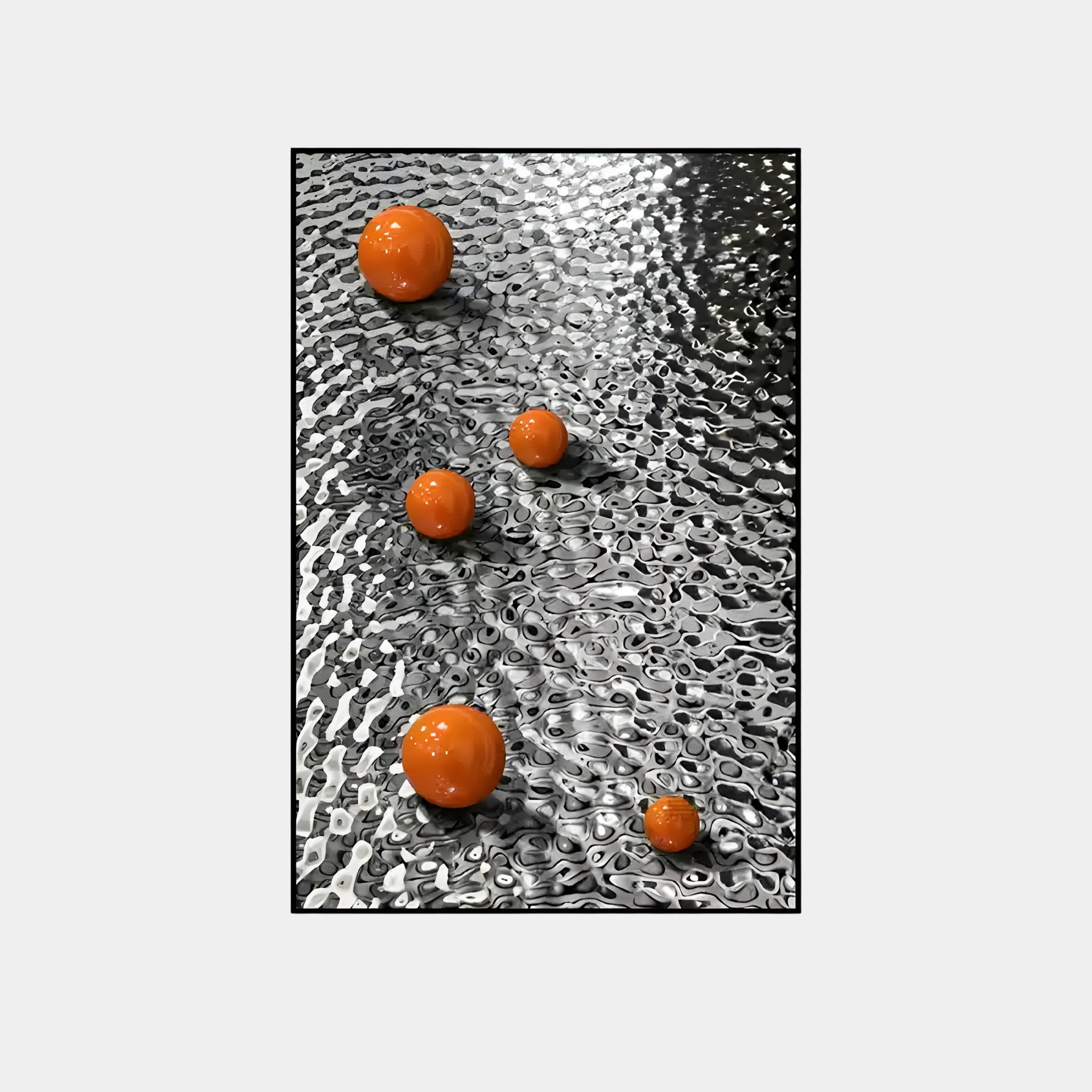 The Luminosa Orange Orb Textured Metal Wall Art by Giant Sculptures features four orange spheres of different sizes on a reflective, wavy metallic surface, embodying modern decor with its unique interplay of color and form.