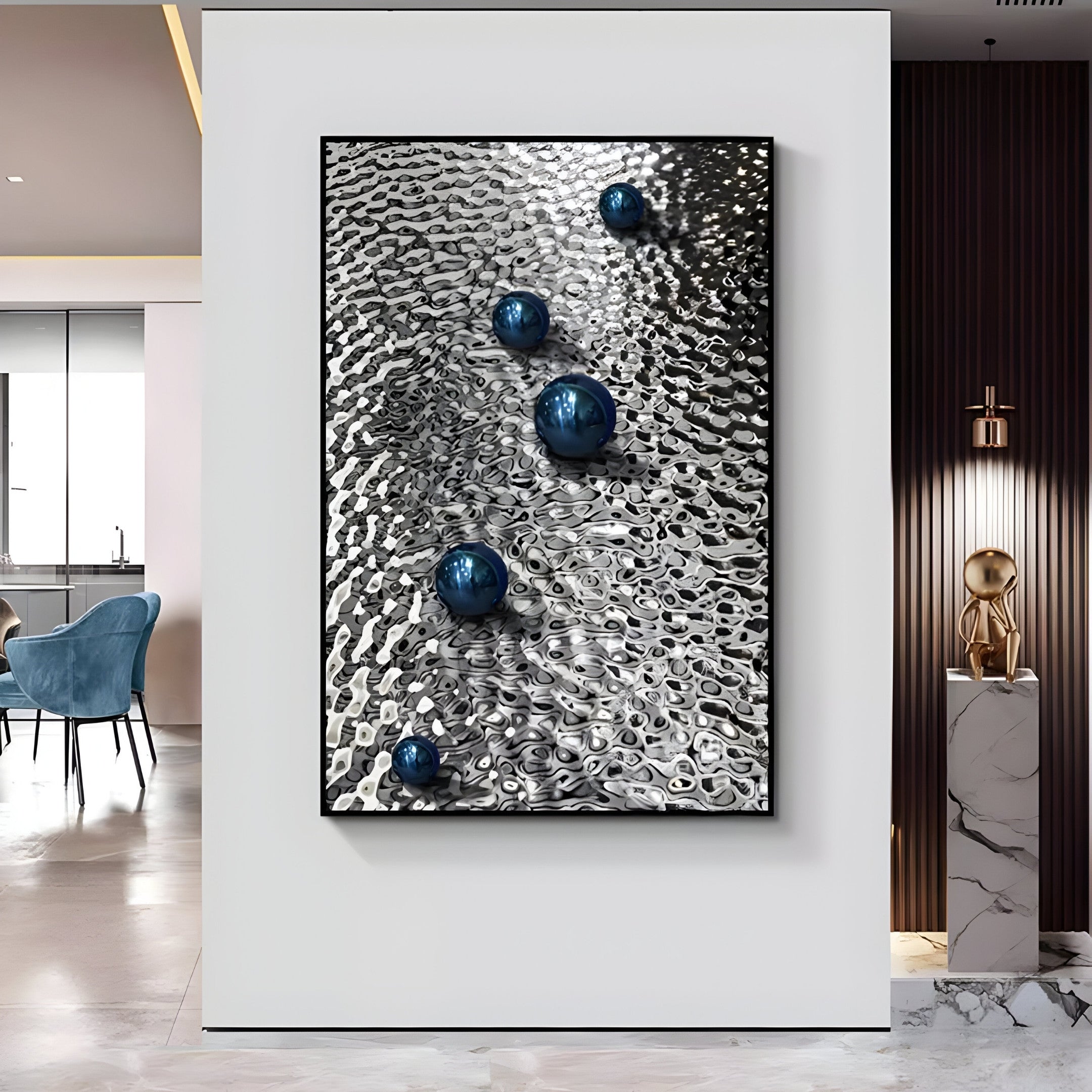 The Luminosa Blue Orb Textured Metal Wall Art by Giant Sculptures showcases five shiny blue spheres on a wavy silver surface. Exemplifying industrial design, its displayed on a white wall near modern interiors with blue chairs and decorative items.