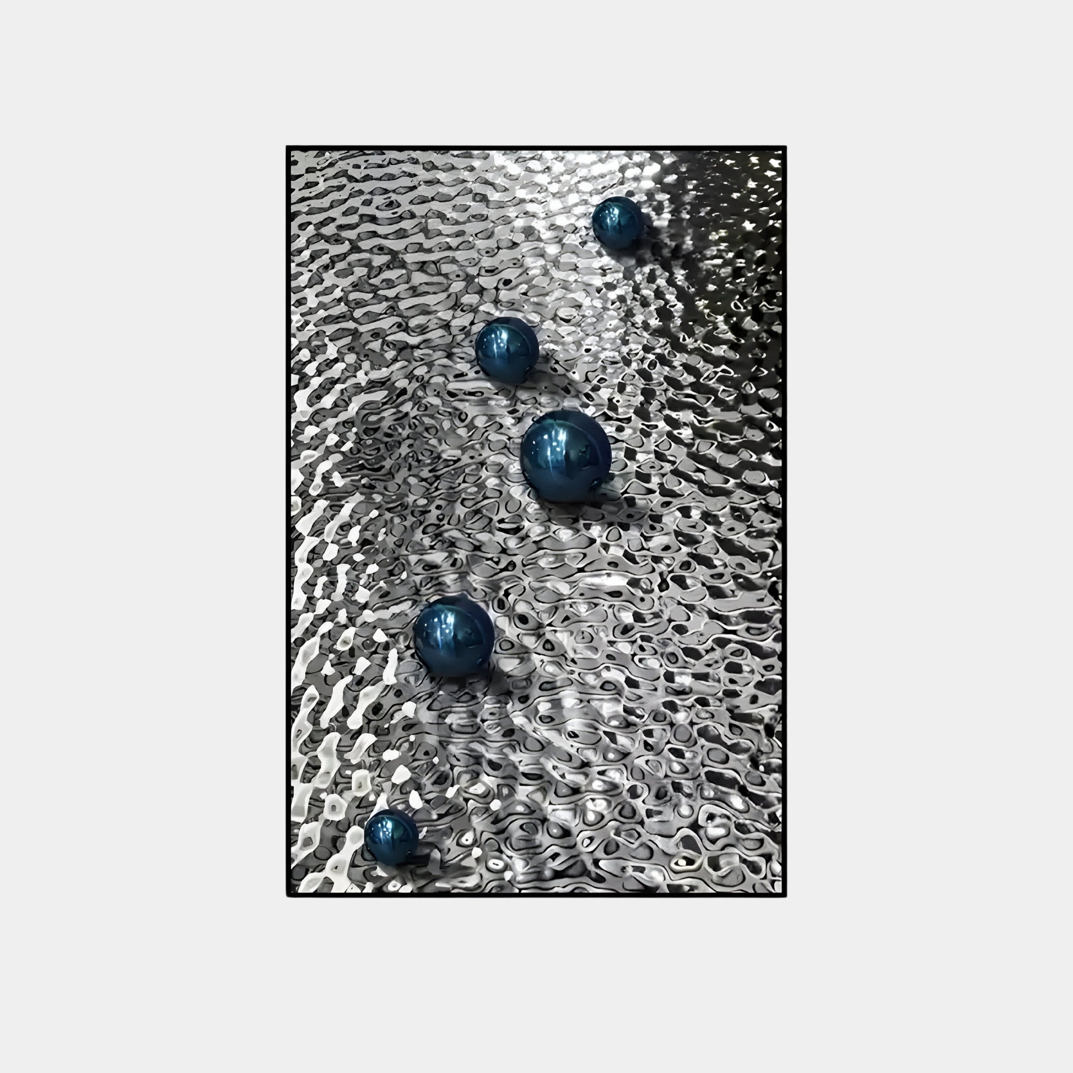 Luminosa Blue Orb Textured Metal Wall Art by Giant Sculptures features blue orbs on a wavy silver surface, crafting an abstract pattern. The industrial design suggests movement, with light and shadow enhancing the visual depth of this masterpiece.