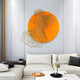 A modern living room exudes contemporary elegance with a white sectional sofa accented by monochrome throw pillows. The wall features the Cellura Orange Geometric Layered Gold Wired Metal Wall Art by Giant Sculptures, and a small orange table adorned with decorative items completes the stylish ensemble.