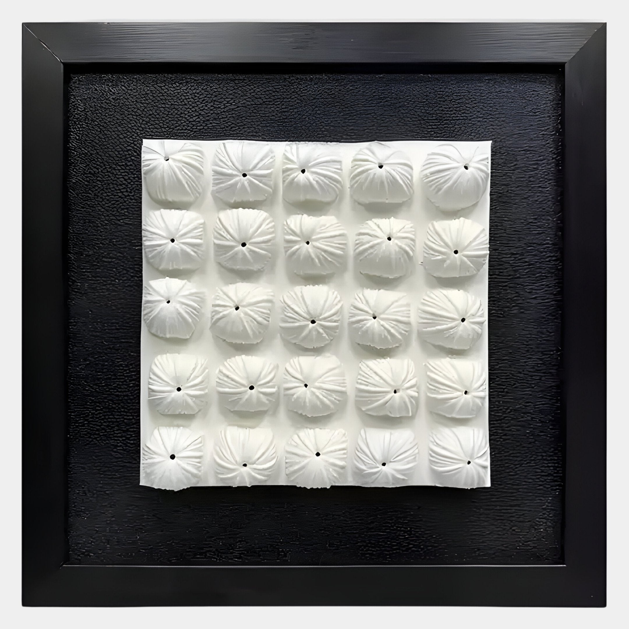 The Harmonia 3D Floral Grid Sculpture With Black Frame by Giant Sculptures features a black-framed square grid of 16 white, pillow-like ceramic forms with central holes—an ideal modern accent for your interior.