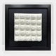 The Harmonia 3D Ceramic Floral Wall Sculpture by Giant Sculptures features 16 white, dome-like, floral forms with central indentations on a textured black background, presented in a black frame and acrylic box—ideal for modern interiors.