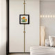 In a neutral-toned modern minimalist bedroom, the Ecliptica Sunflower Botanical Illustration Gold Frame Wall Art by Giant Sculptures is centered on a vertical accent line for botanical flair. The decor includes a white bed, soft pillows, and a chic floor lamp.