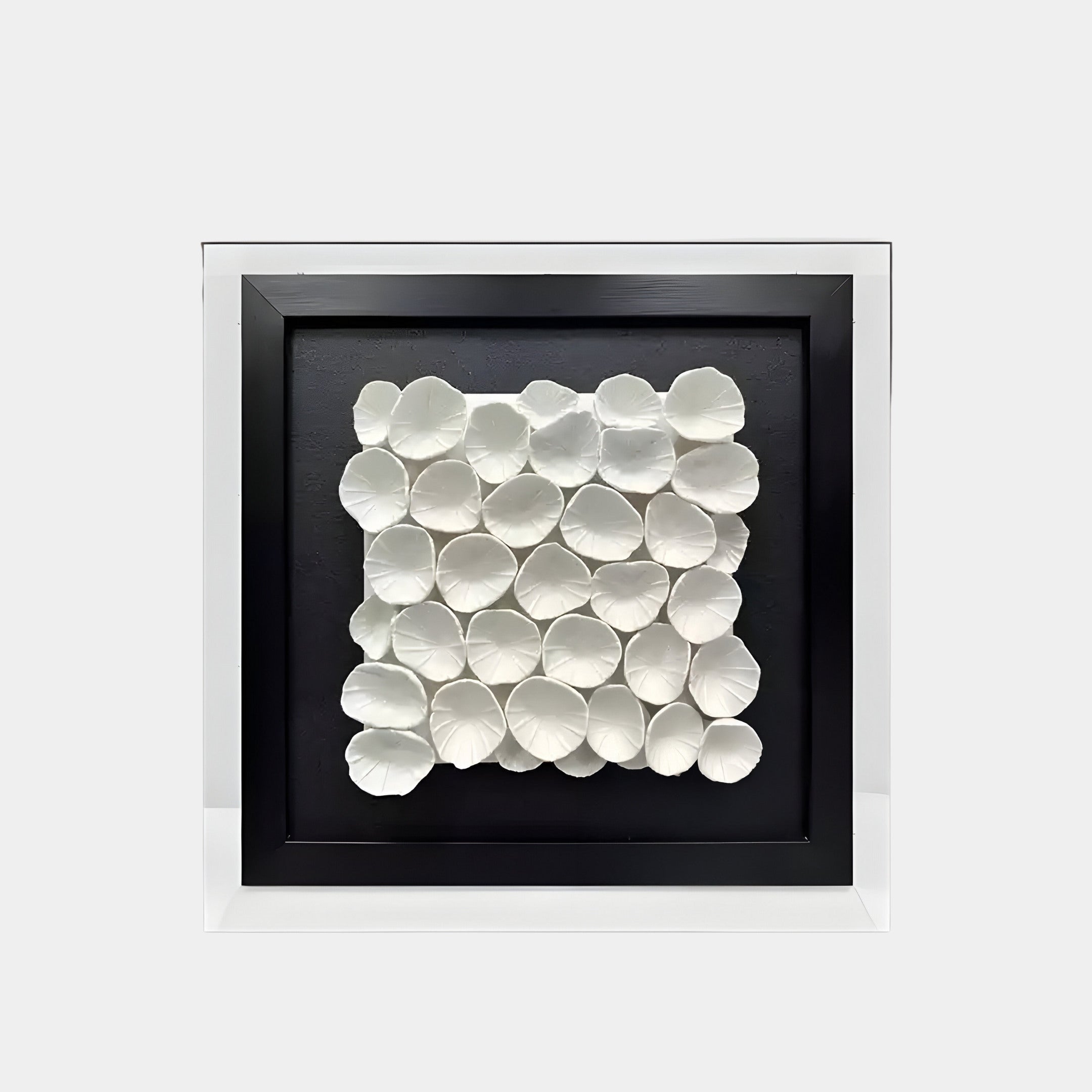 The Harmonia 3D Ceramic Petal Wall Sculpture by Giant Sculptures features white, petal-like shapes in a grid within a black square frame, combining organic elegance with a modern sculptural aesthetic.