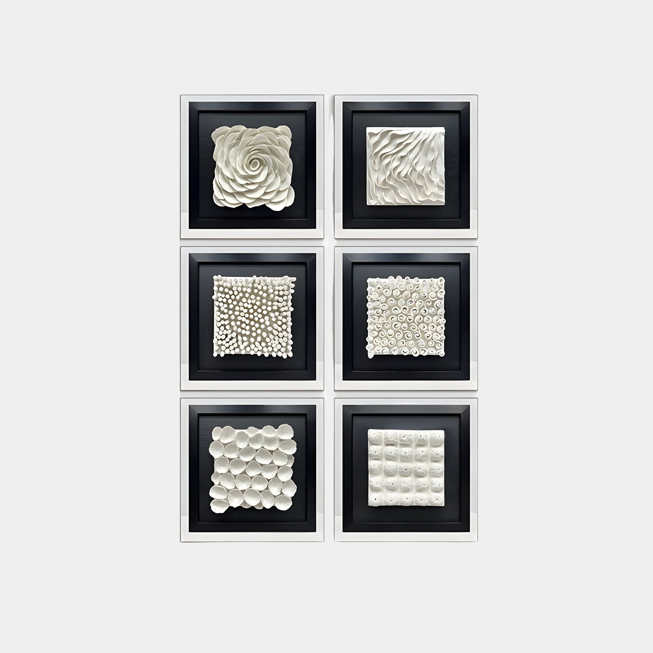 The Harmonia Set of 6 3D Ceramic Wall Sculptures by Giant Sculptures adorns the wall in two vertical columns, showcasing modern design through white, textured surfaces with spirals, ridges, and circular shapes on a black background for an impactful display.