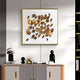 A modern interior showcases a cabinet with decorative items, including two abstract figurines and a small plant. Above, the Brassica Gold Leaf Metal Square Wall Art by Giant Sculptures adorns the wall, adding contemporary luxury to the space.