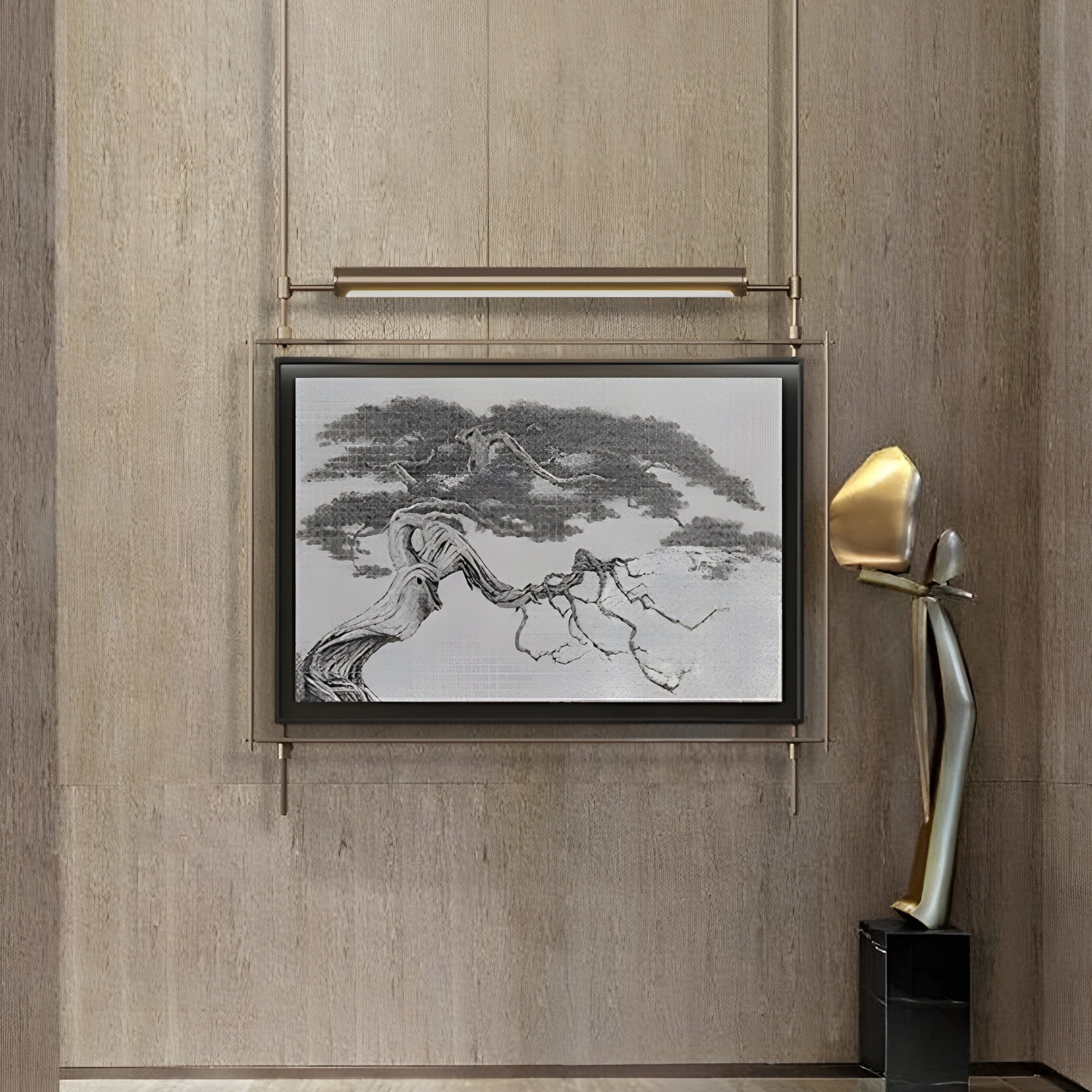 A Celestique Ancient Bonsai Framed LED Wall Art hangs on a beige wall, its monochrome tones accented by an elegant tall abstract sculpture. Featuring a slender figure with a gold-colored head and elongated limbs, it stands in harmony like art from Giant Sculptures.