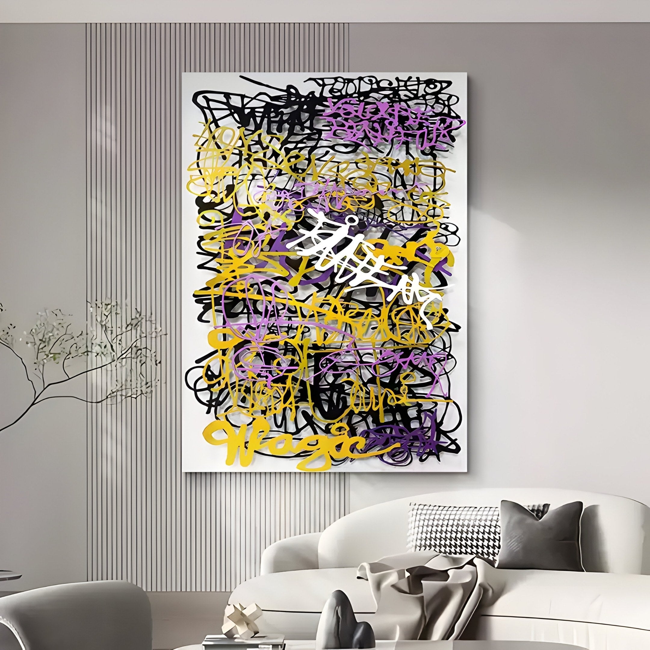 A modern living room features the Scriptura II Multicolour Graffiti Expression metal wall art by Giant Sculptures, boasting bold black, purple, and gold layers. It hangs above a white curved sofa with monochrome pillows while a minimalist dried branch adds a contemporary touch.