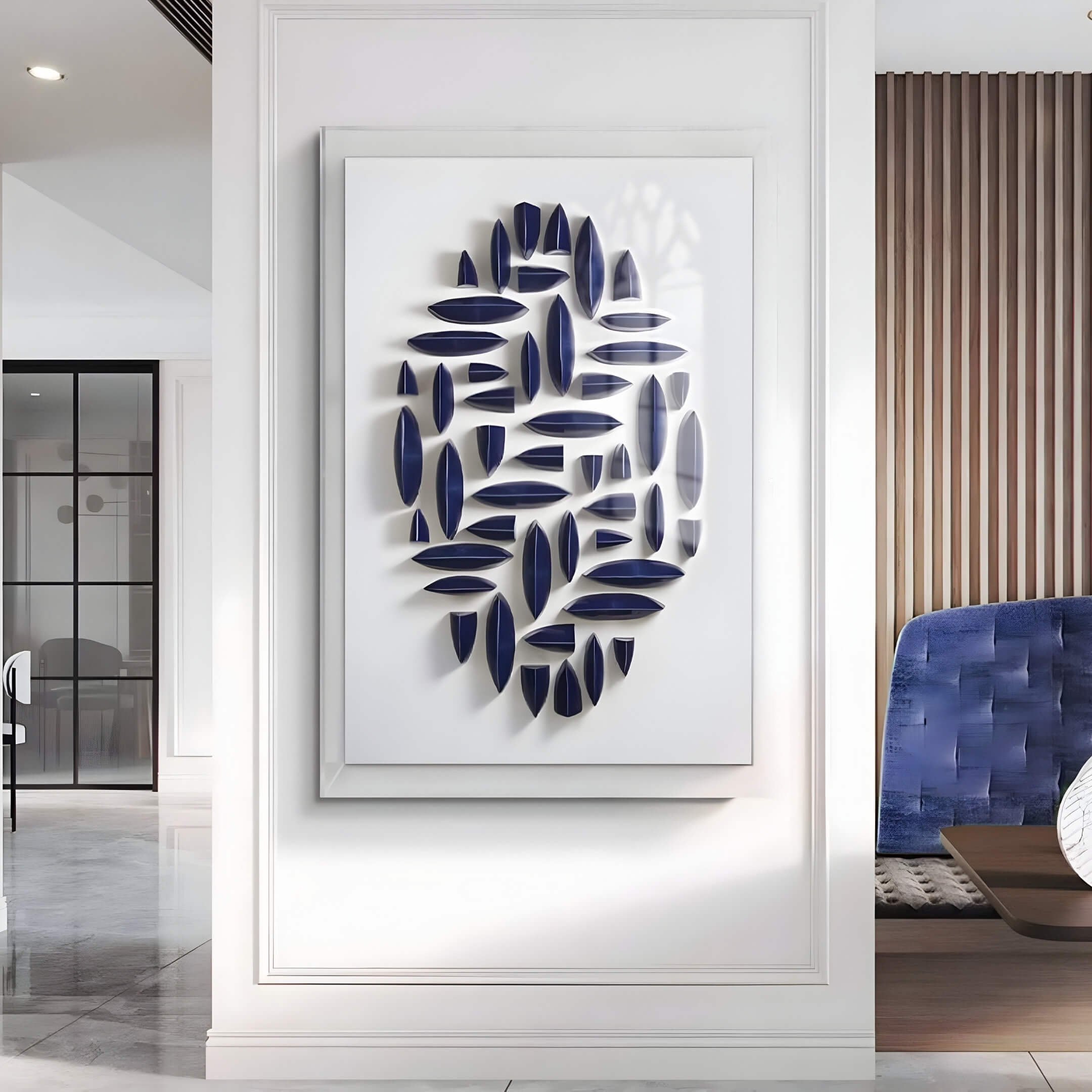 The Elysian 3D Ceramic Wall Art in Rhythmic Navy Blue by Giant Sculptures enhances a modern interior. It is centered on a white wall with vertical paneling and flanked by glass doors, complemented by a stylish blue chair in the corner for an elegant setting.