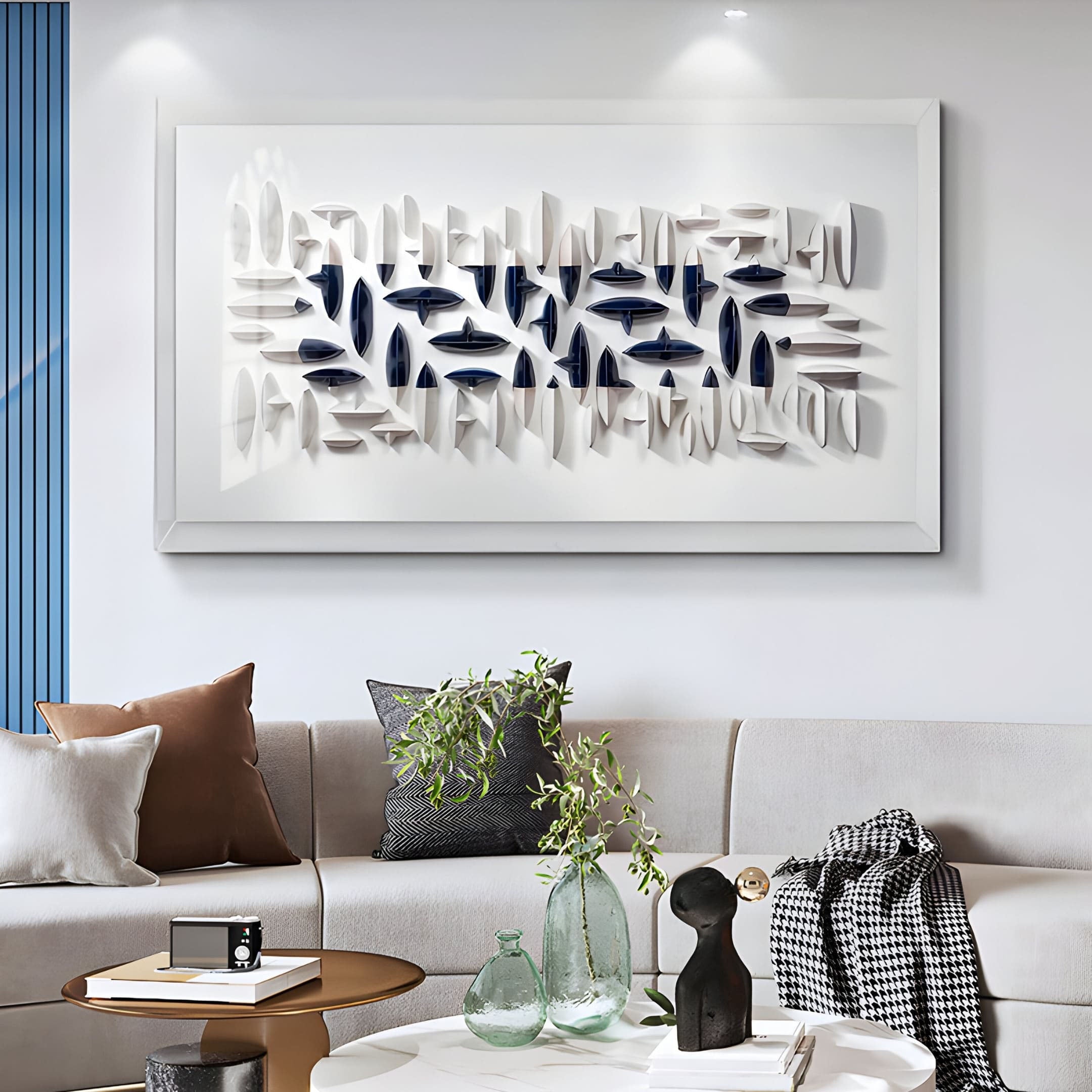 A modern living room features a white sectional sofa with colorful cushions. A Giant Sculptures Elysian 3D Ceramic Wall Art with an abstract navy blue and white design enhances the contemporary space, complemented by a coffee table with green plants and decor in front of the sofa.