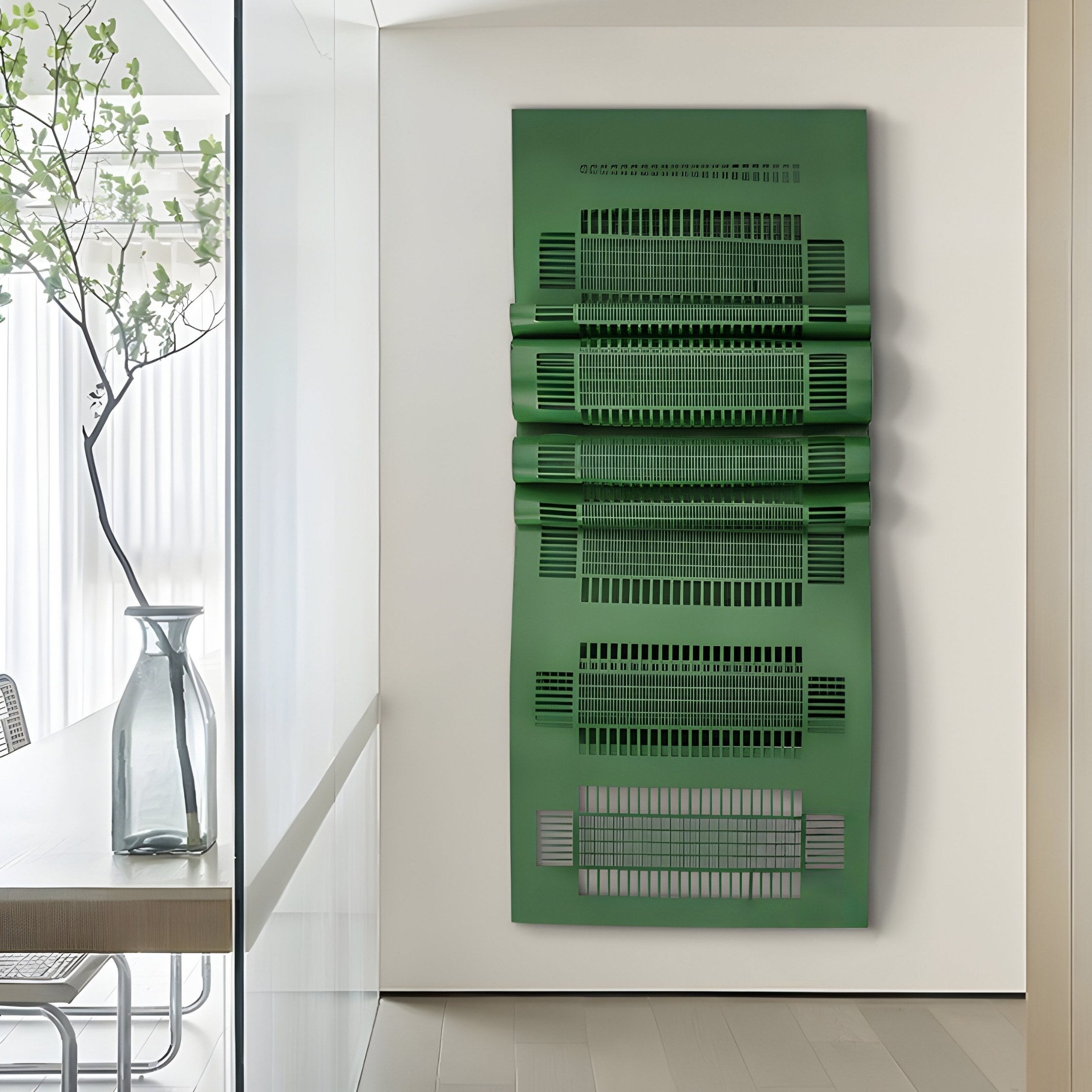 A modern interior is highlighted by the Strata Green Vertical Folded Grid Metal Wall Art from Giant Sculptures, resembling stacked sheets. This metal art complements a glass vase with foliage and a sleek table set, while natural light illuminates the contemporary décor beautifully.