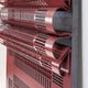 Close-up of a bold red statement, the Strata Red Vertical Folded Grid Metal Wall Art by Giant Sculptures showcases curved, overlapping burgundy panels with perforated patterns. This dynamic design creates a layered look against a dark background, ideal for contemporary interiors.