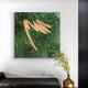 Hanging on a white wall is the Plisse Verdant Green Textured Abstract Wall Art by Giant Sculptures, featuring crumpled green textures and tan strokes. Below, a black bench sits beside a gold vase holding slender-branched plant.