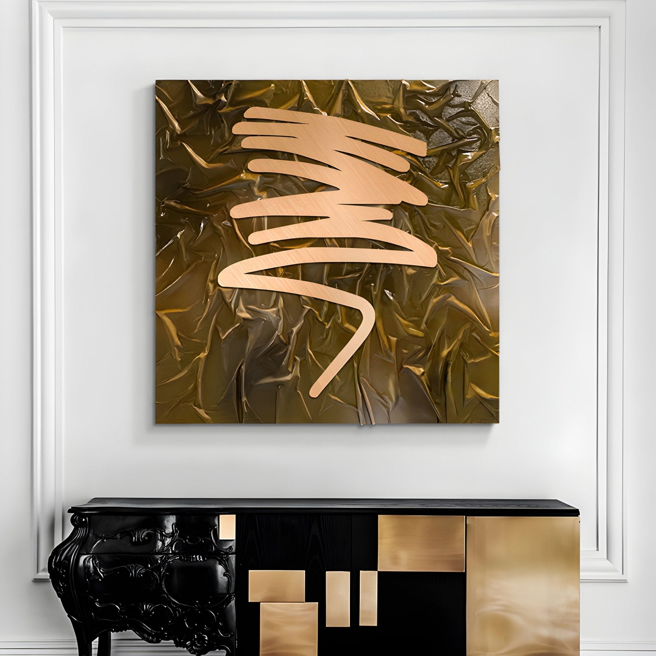 The Plisse Golden Ochre Textured Abstract Wall Art by Giant Sculptures, with its gold brushstrokes against a dark background, hangs on a white wall. Below it stands a contemporary black and gold console table featuring geometric patterns that highlight modern craftsmanship.