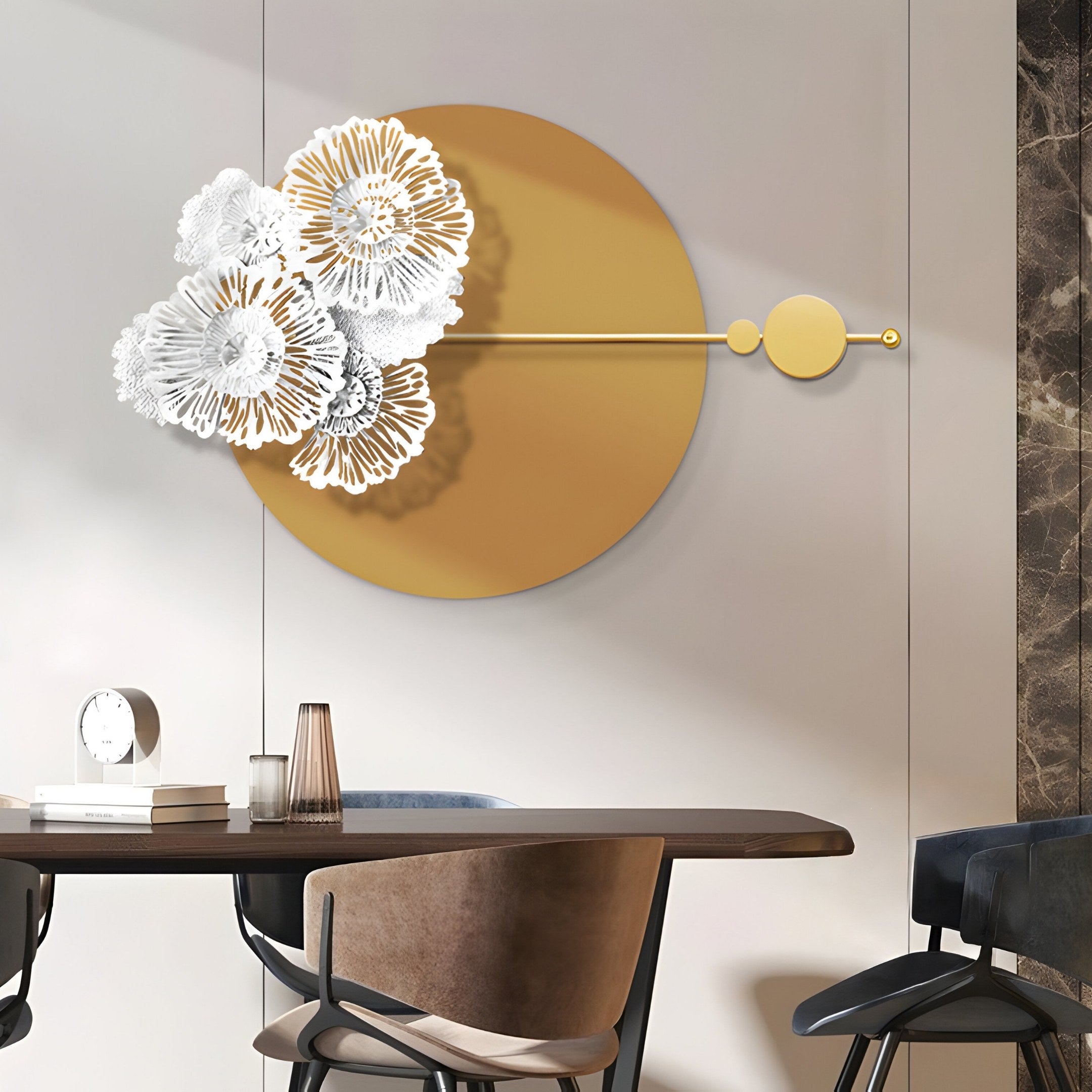 Enhance your decor with the Blossom Halo Golden Bloom Round Floral Decorative Wall Art from Giant Sculptures. A large golden circle with white floral designs complements a light wall. Below, a modern wooden table, chairs, and a cylindrical lamp complete the look.