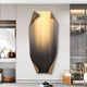 A modern living room features Giant Sculptures Celestial Midnight Gradient Edge Folded Abstract Metal Wall Art, with golden streaks and curled edges. A woven basket, cushions, and a small side table enhance the cozy, contemporary atmosphere.