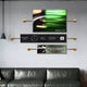 Above the green leather sofa, the wall display presents three mounted Visario Rolex Inspired Luxury Metal Wall Art pieces by Giant Sculptures, featuring a Rolex watch face and logo with phrases like Superlative Chronometer.