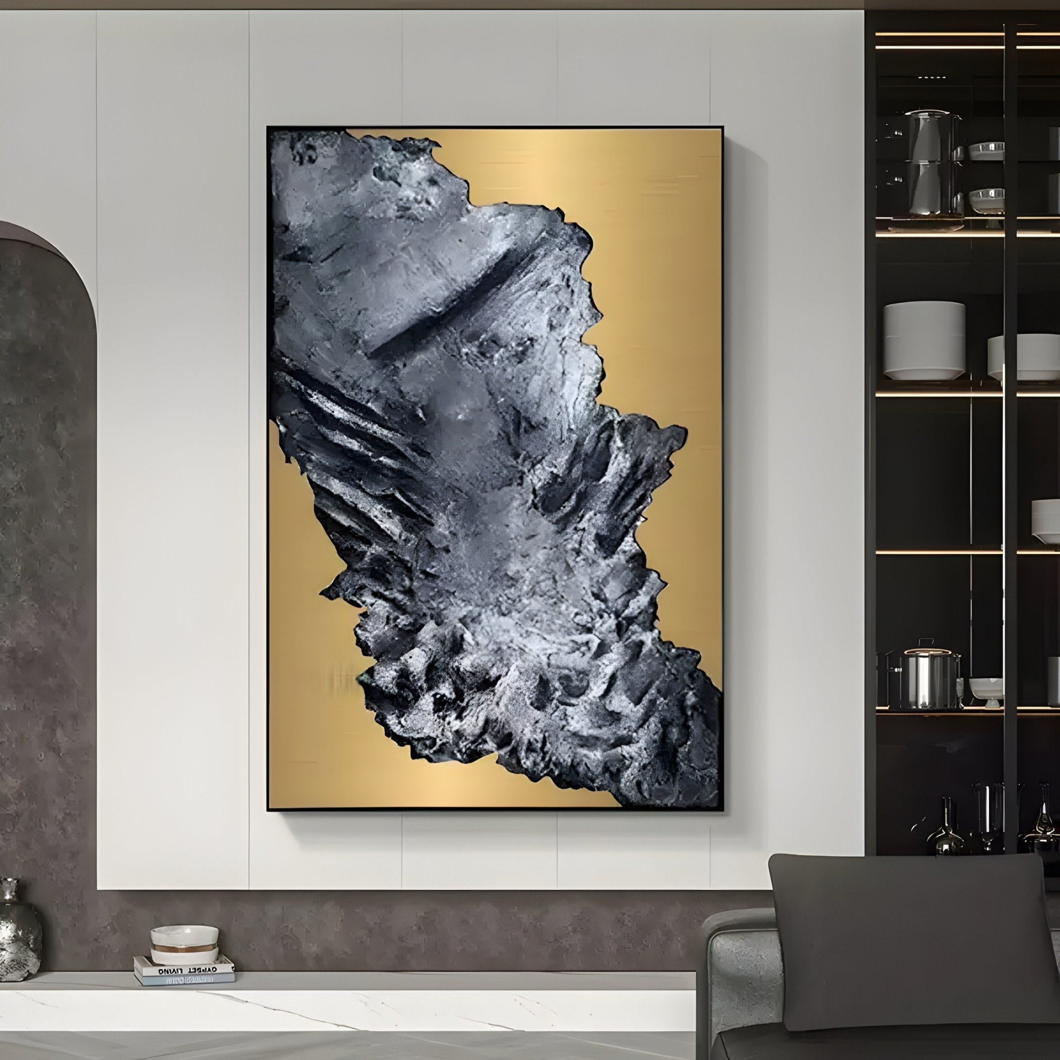 A modern living room embodies contemporary design with Giant Sculptures Terranica Metallic Crust Textured Abstract Metal Wall Art in a gold finish on a white wall. The space features a gray chair, built-in shelf with decor, and soothing neutral tones.