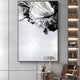 A modern living room displays the Terranica Monochrome Flow Textured Abstract Metal Wall Art by Giant Sculptures. Its black and white textures complement a small table with decor below, while shelves to the right hold books. A partially visible brown chair adds warmth to the stylish space.