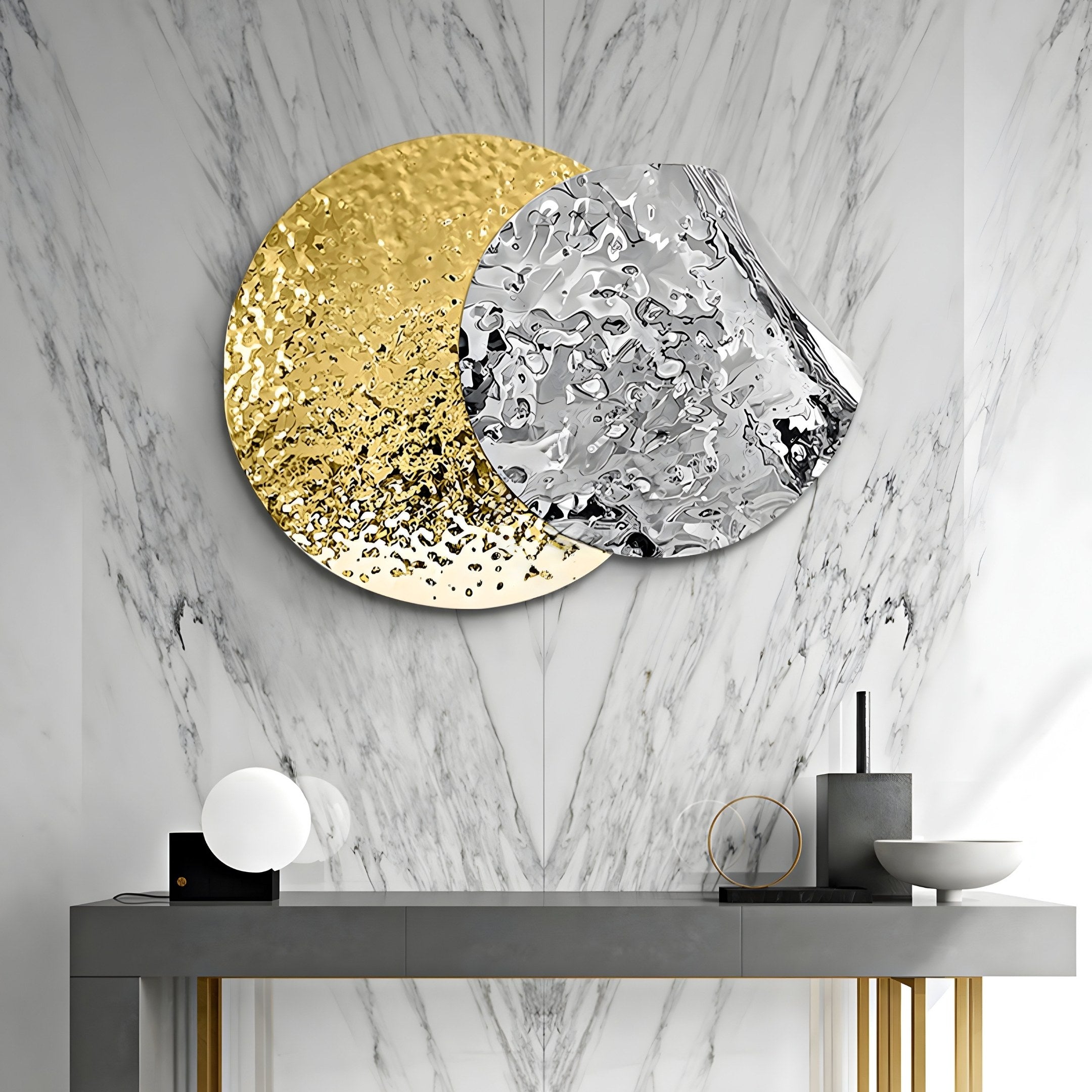 A modern interior design features the Metaluxe IV Gold & Silver Dual Disc Textured 3D Wall Art by Giant Sculptures on a marble wall. Beneath it, a sleek console table displays a sculptural lamp, small bowl, and decorative ring, creating an ideal modern statement piece.