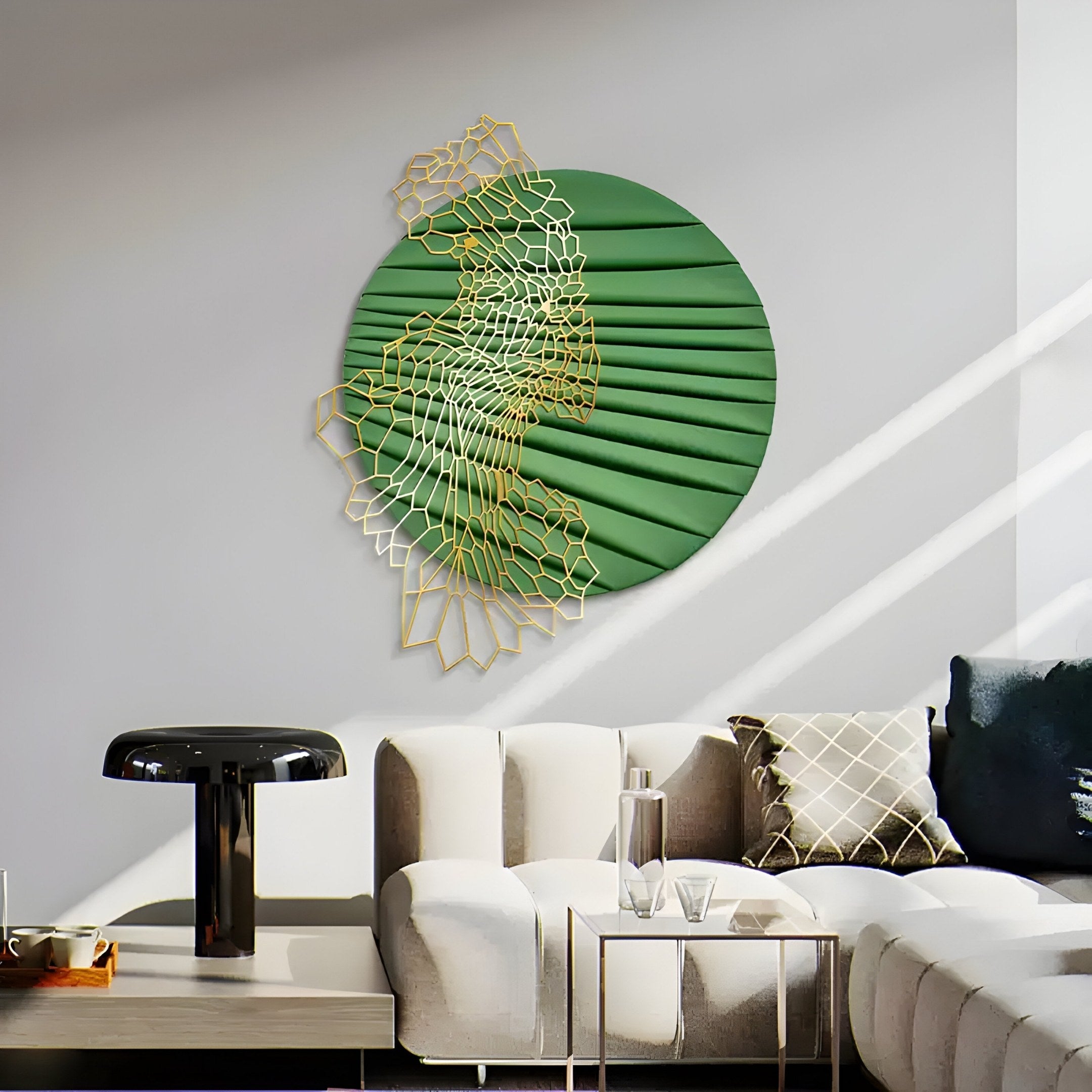 A modern living room features a white sectional sofa with decorative pillows, a black side table, and the Auramesh Forest Green-II Metal Winged Circular Geometric Wall Art by Giant Sculptures on a gray wall illuminated by natural sunlight.