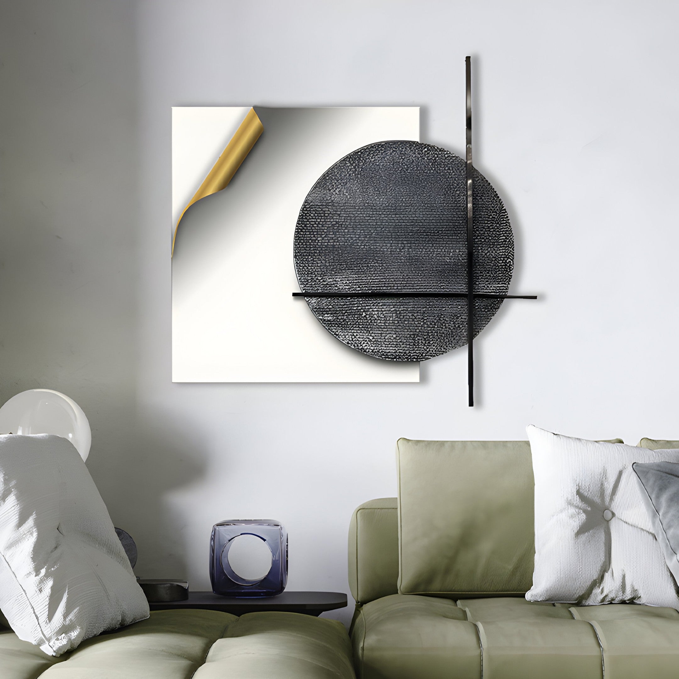 A modern living room showcases a beige sectional sofa with white and gray pillows. Adorning the wall is the Tesselle White Metal Fold & Grey Textured Geometric Wall Art by Giant Sculptures, featuring a black circle and metallic lines. A clear cube decor piece sits on the sofa arm, enhancing the contemporary vibe.