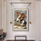 The Aristo Napoleon On Horseback Painting Gold Frame Hanging Wall Art by Giant Sculptures features a historical figure in a blue coat, yellow pants, and red cloak on a rearing horse against rocky mountains, elegantly displayed above a cushioned bench.