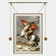 The Aristo Napoleon On Horseback Painting Gold Frame Hanging Wall Art by Giant Sculptures features Bonaparte in a red cape and uniform against moody clouds, elegantly suspended from a gold rod with decorative weights.