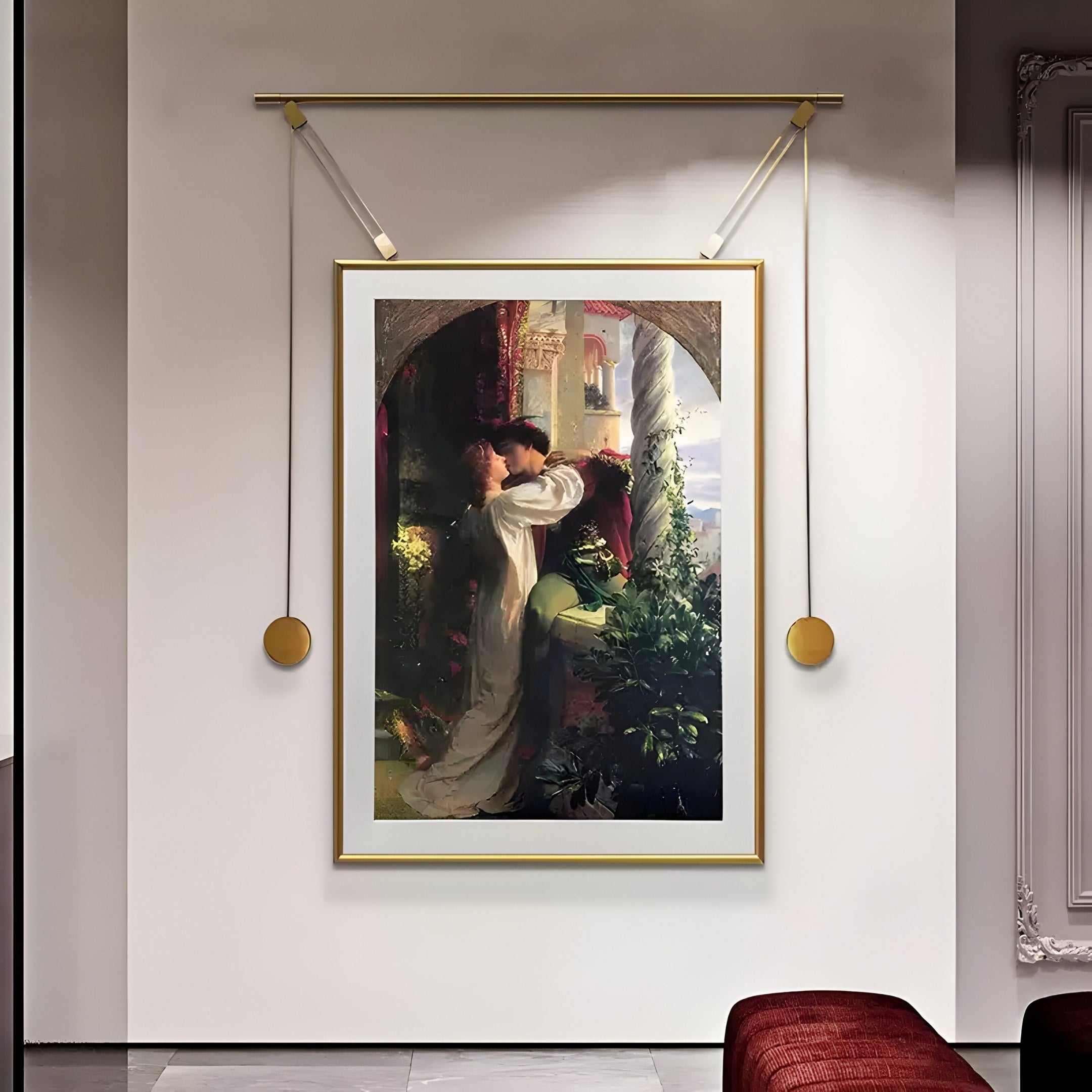 The Aristo Balcony Romance Painting by Giant Sculptures, elegantly framed in gold, portrays a timeless love scene with a couple embracing by a garden archway. The scene is highlighted by two circular lights, with a plush red bench below, inviting you to linger in its enchanted glow.